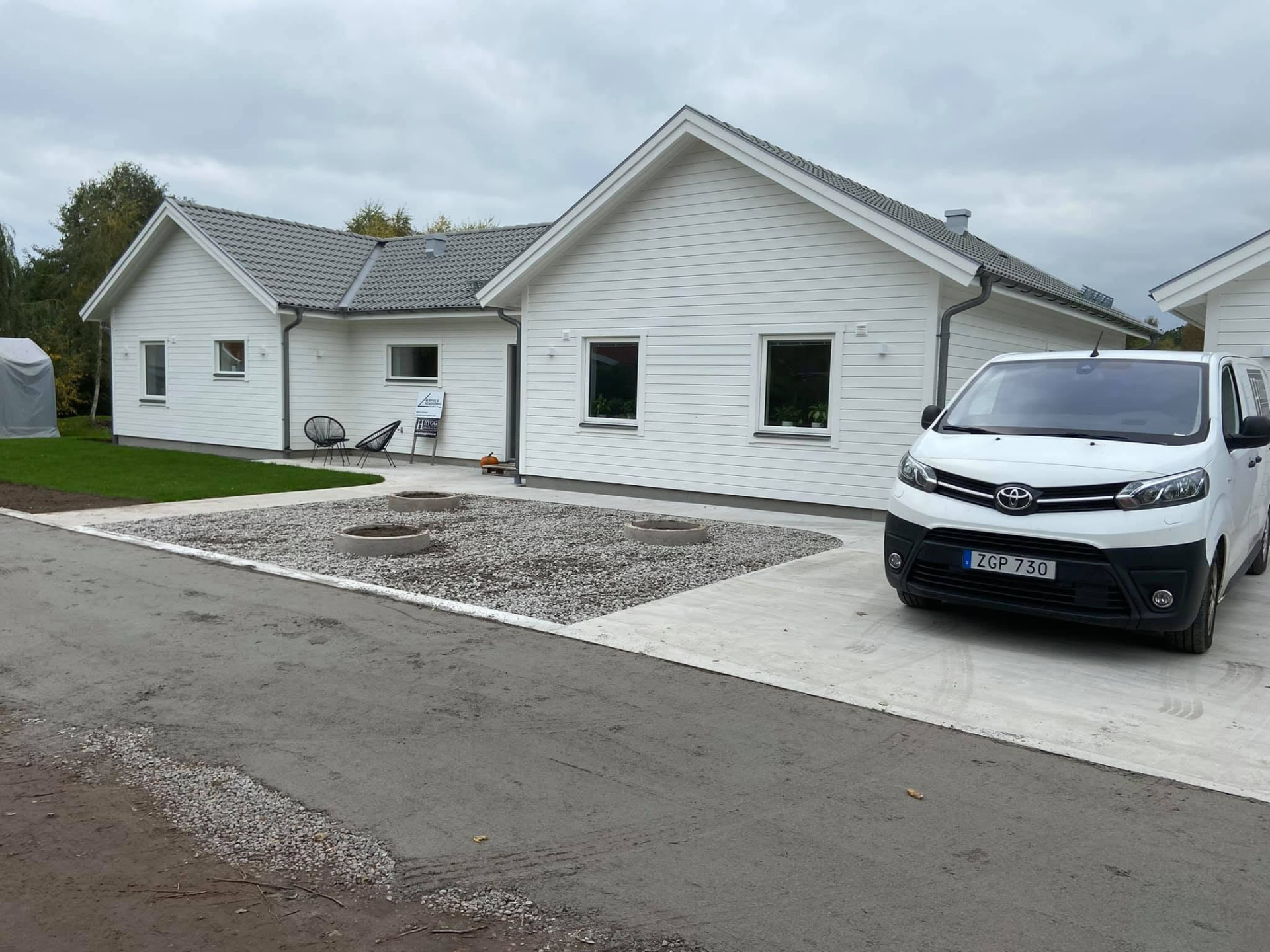 Nybyggd vit villa i Kalmar med grått tegeltak och H Byggs servicebil på uppfarten